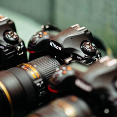 Upper angle view of a Nikon DSL camera with two others out of focus on either side.